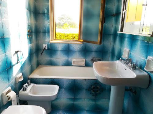 a blue tiled bathroom with a sink and a toilet at Incantevole Villa Maddalena in Otranto
