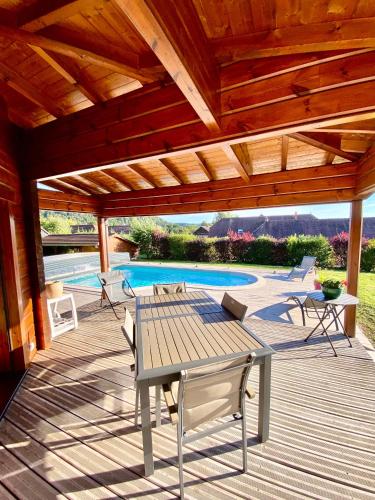 a wooden deck with a table and chairs next to a pool at Chalet des Lacs in Marigny