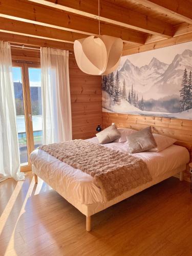 a bedroom with a bed with a painting on the wall at Chalet des Lacs in Marigny