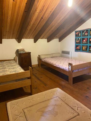 two beds in a room with wooden ceilings and wooden floors at Buvolaccia in Sampolo