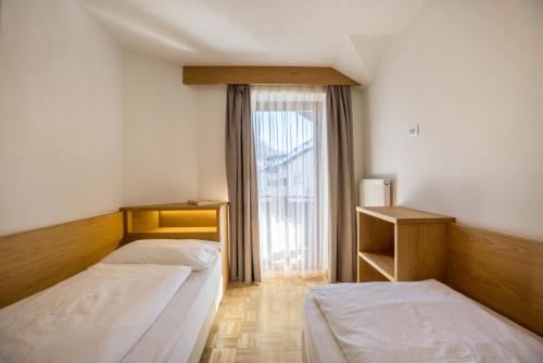 two beds in a room with a window at Rosalpina Apt 2 in San Vigilio Di Marebbe