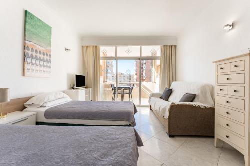 a bedroom with two beds and a couch and a window at Sunny studio with seaview in Fuengirola