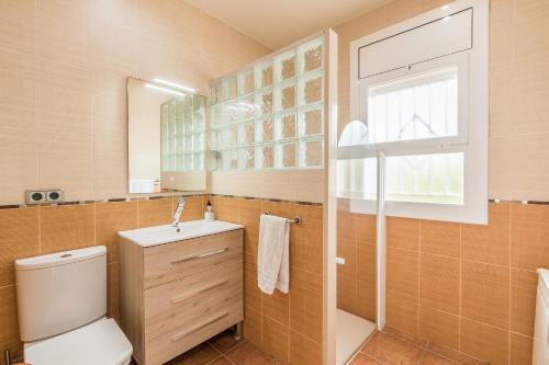 a bathroom with a toilet and a sink and a window at Can Fogars in Fogás de Tordera
