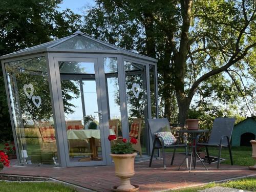 a greenhouse with a table and chairs in a yard at Ferienhof Renate Sassen in Werdum