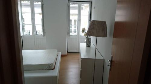 a living room with a white chair and a lamp at Faro City Center Apartment I in Faro