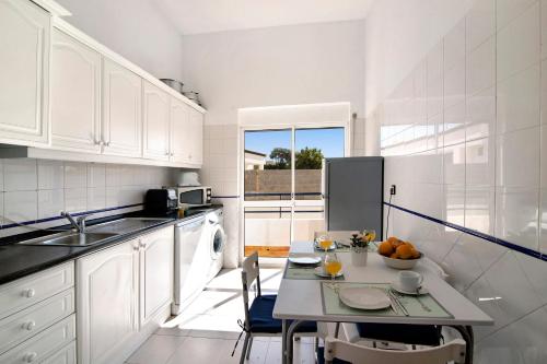 a kitchen with white cabinets and a table with fruit on it at Apartamento Solário in Armação de Pêra