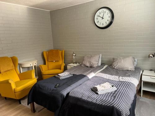a bedroom with a bed and two chairs and a clock at Kangaskartano Yksiö in Keitelepohja