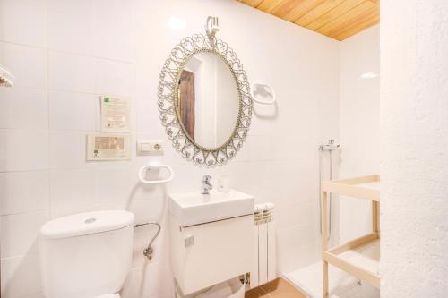 a white bathroom with a toilet and a mirror at Sant Grau ii in Navés