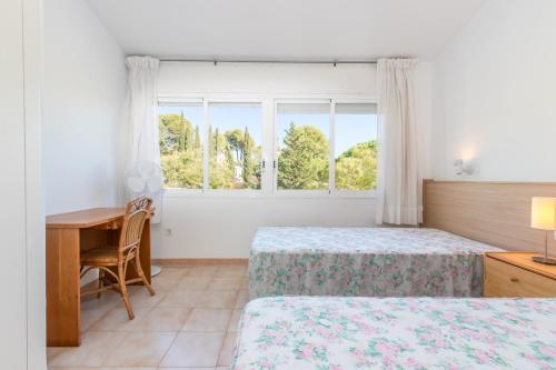 a bedroom with two beds and a desk and a window at Fantàstic s'agaró in S'agaro
