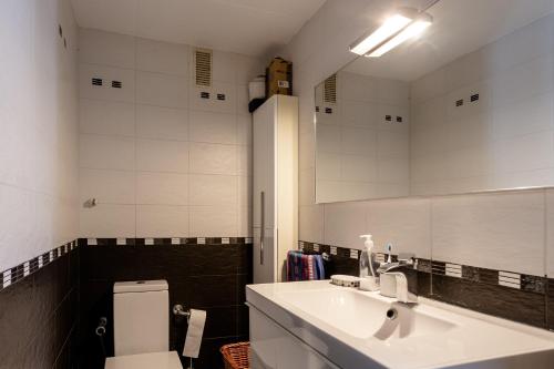 a bathroom with a sink and a toilet and a mirror at Apartamento Costa Brava in Blanes