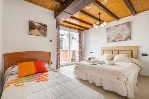 two beds in a bedroom with white walls and wooden ceilings at Casa Petra in Illora