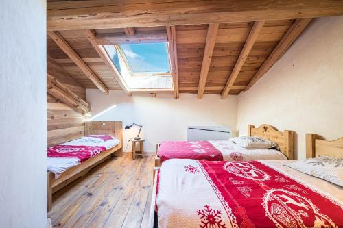two beds in a room with wooden floors and a window at Chalet La Grange des Flocons in Valloire