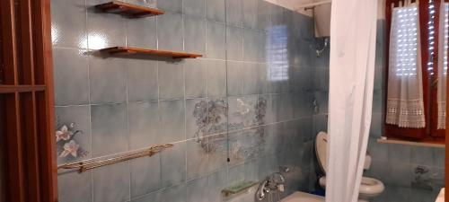 a bathroom with a blue tiled wall with a toilet at B e B Beglia Alguer in Alghero