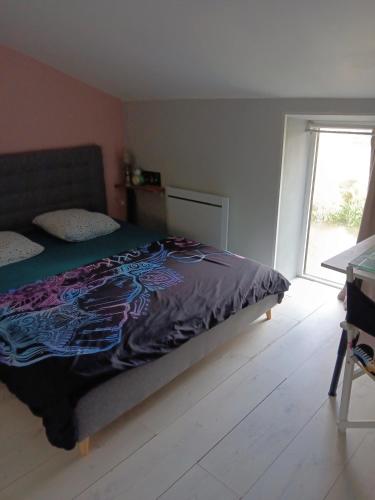 a bedroom with a bed with a purple comforter and a window at Maison Au Bord de l'eau in Loches