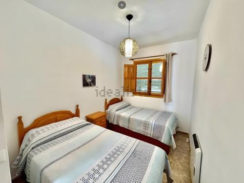 two beds in a room with white walls at Apartamento Rey Melchor in Trevélez