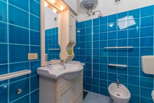 a blue tiled bathroom with a sink and a toilet at Quadrilocale 800mt dal mare in San Teodoro