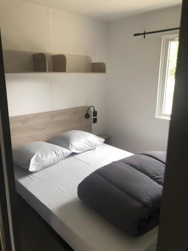 a bedroom with a bed and a window at Mobilehome Riviera avec terrasse 47 in Saint-Gervais