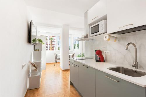 a kitchen with white cabinets and a sink and a counter at Apartamento Lucía in Torre del Mar