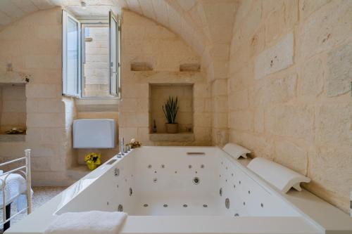 a large white bath tub in a room with a window at Corte Cochlea La Curte Suite per 4 in Cannole