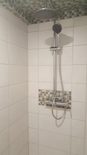 a shower in a white tiled bathroom at Gîte Du Vignal in Mazeyrat-d'Allier