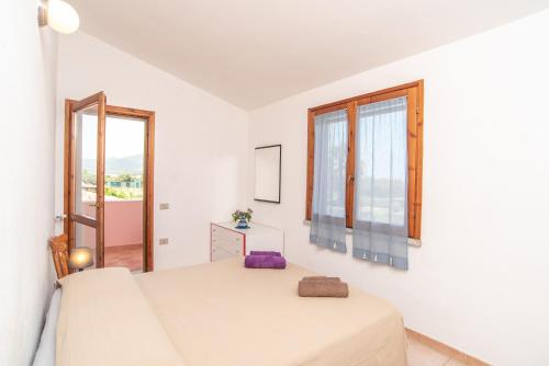 a white bedroom with a bed and a window at Sardegna Budoni giardino e Jacuzzi in Budoni