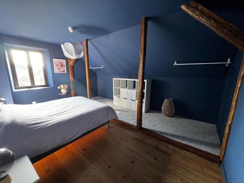 a blue bedroom with a bed and a window at La Buissonnière in Erckartswiller