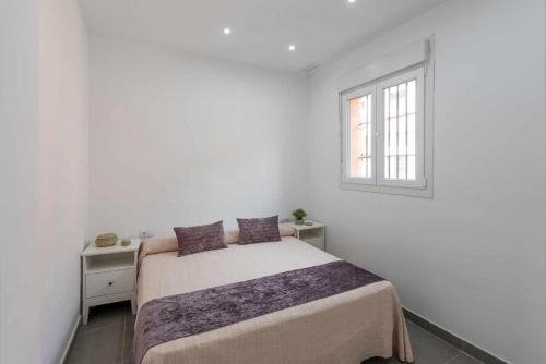 a white bedroom with a bed and a window at Apartamento Torero ii in Marchena