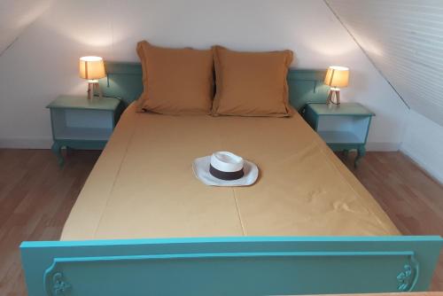 a blue bed with a hat on it with two tables at Le Gîte d’Ambre in Poullaouen