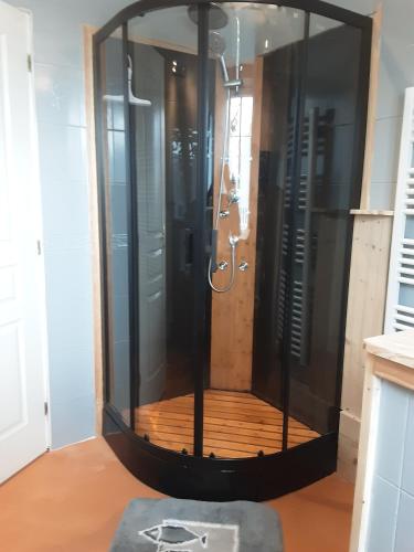 a shower with a glass enclosure in a room at Le Gîte d’Ambre in Poullaouen