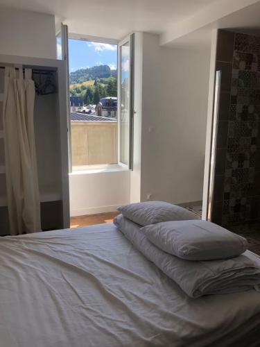 a bed with pillows on it in a room with a window at Famille in La Bourboule