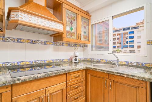 a kitchen with wooden cabinets and a sink and a window at Playa Algarrobo Costa in Algarrobo-Costa