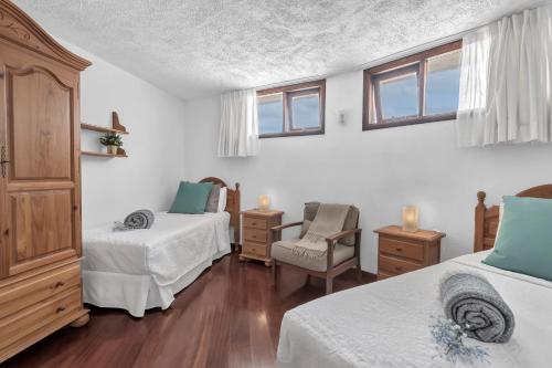 a bedroom with two beds and a chair and windows at Villalmar in Famara
