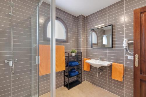 a bathroom with a sink and a shower with orange towels at Casa Fama con piscina privada clima in Yaiza