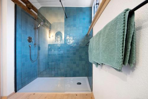 a bathroom with a shower with blue tiles at Armenhaus 1828 in Görisried