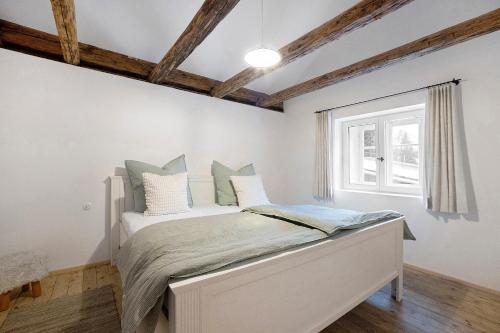 a bedroom with a bed with white walls and a window at Armenhaus 1828 in Görisried