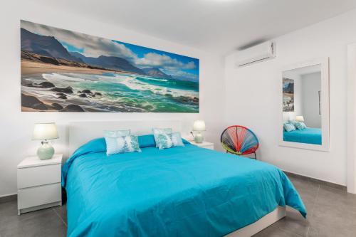 a bedroom with a blue bed and a painting on the wall at Sparrow in La Santa