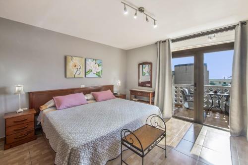 a bedroom with a bed with pink pillows and a balcony at Casa Carolina Y Roger Tazacorte in Tazacorte