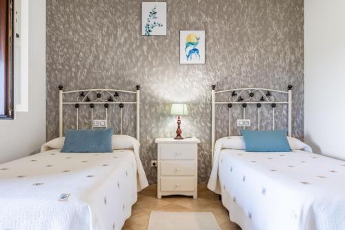 two beds in a room with white sheets and blue pillows at Las Candelas - Las Sopeñas in Oreña