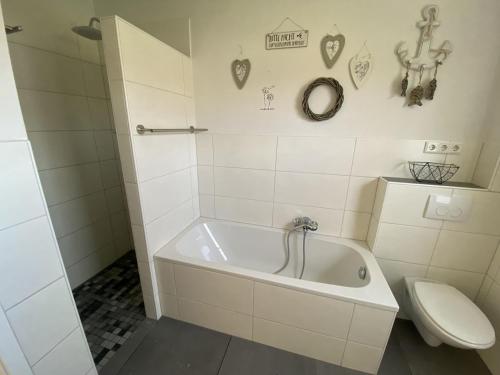 a white bathroom with a tub and a toilet at Ferienwohnung Repetal in Attendorn