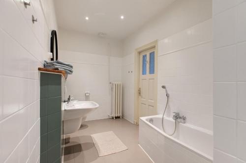 a white bathroom with a tub and a sink at Sophienhof in Kronprinzenkoog