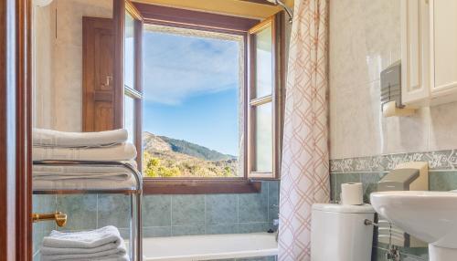 a bathroom with a window and a tub and a sink at Casa Collado Santo Tomás in El Collado