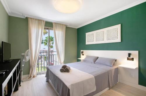 a bedroom with green walls and a bed and a television at Costa Bella la Tejita in La Tejita
