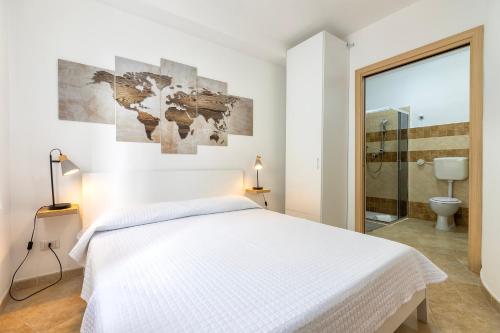 a white bedroom with a bed and a bathroom at L'angolo Porto Torres in Porto Torres