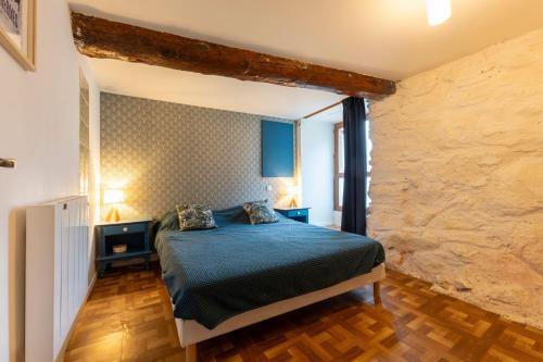 a bedroom with a bed and a stone wall at Gite d'Orgeix - Ax-les-Thermes in Orgeix