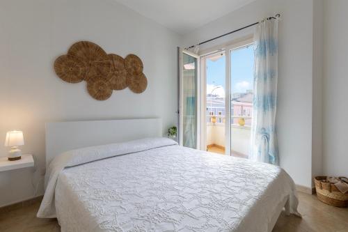 a white bedroom with a bed and a large window at L'angolo Porto Torres in Porto Torres