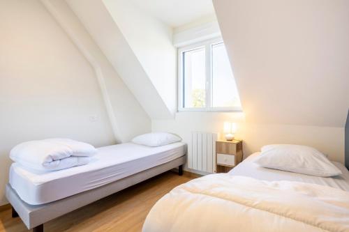two beds in a room with a window at Résidence des Saules in La Forêt-Fouesnant