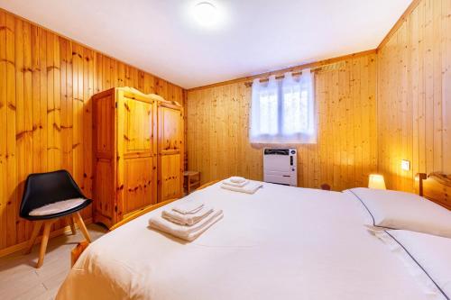 a bedroom with a white bed and a chair at Casa Fiocco di Neve in Vigo di Cadore