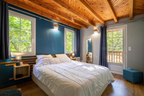 a bedroom with a large bed with blue walls and windows at Gite Au pied du Pic du Midi in Campan
