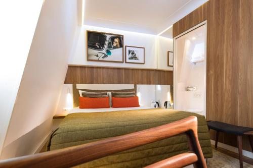 a bedroom with a green bed with orange pillows at Hôtel Eiffel Turenne in Paris