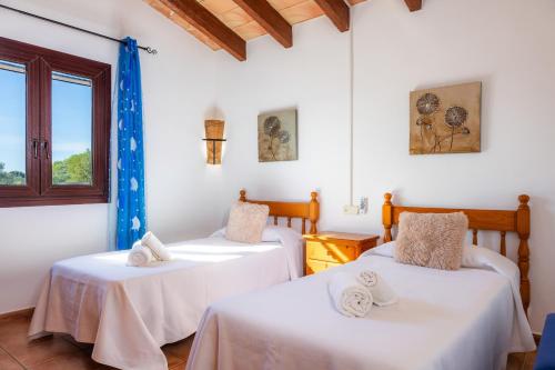 two beds in a room with white walls and a window at Can Pota in Portocolom